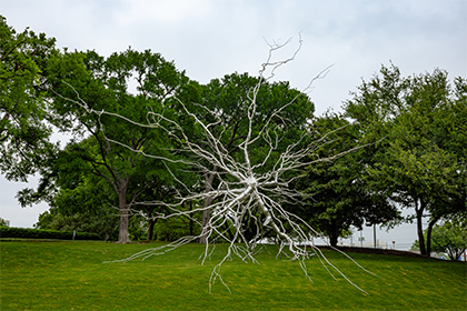 large outdoor sculpture with green trees in background