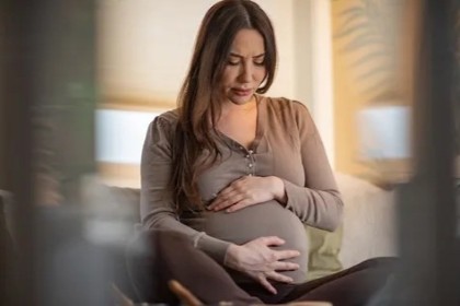 seated pregnant woman holds her belly