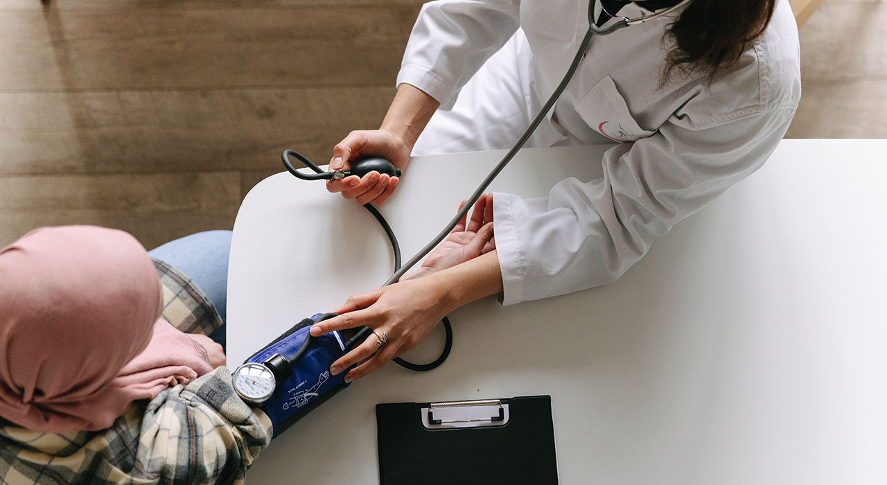 An overhead photograph of a doctor taking blood pressure of seated patient