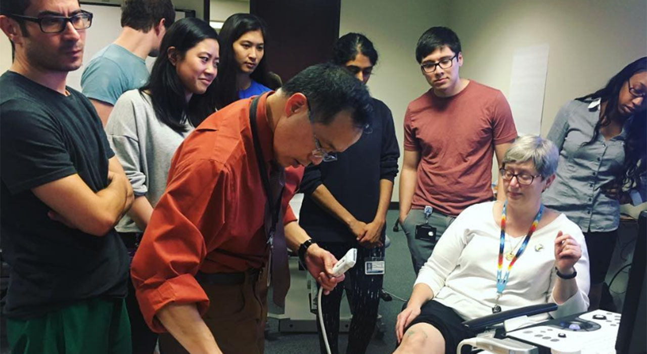A group of students watch a demonstrtion of an ultrasound device