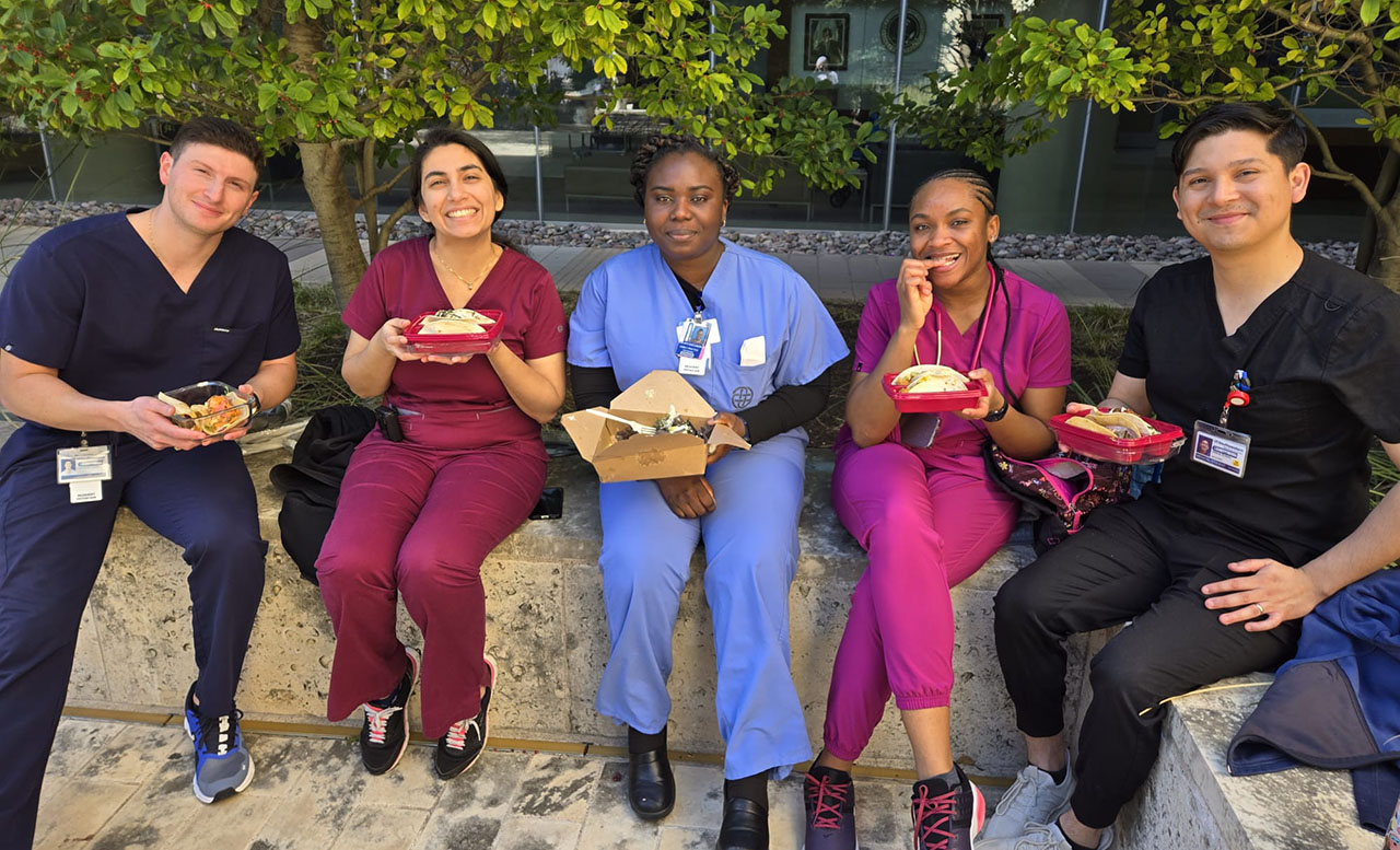 A group of residents smiling and holding plates of tacos