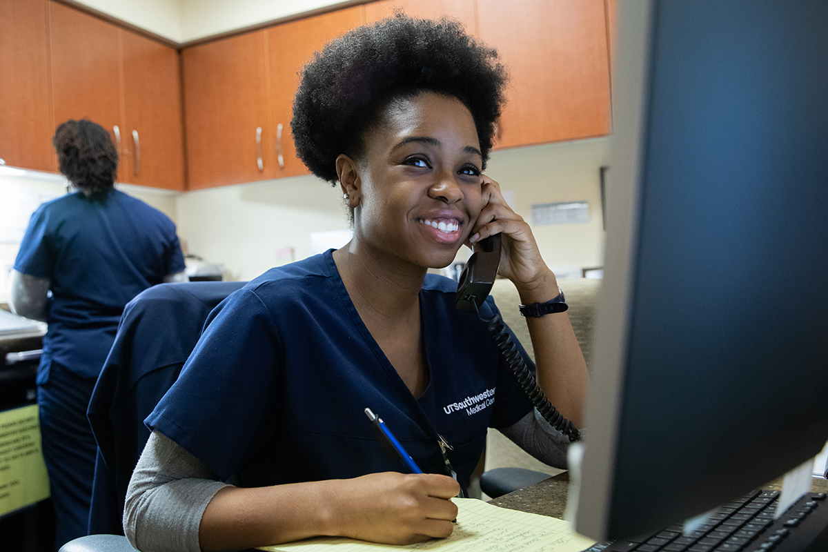 a nurse seated at a computer ansering a phone call