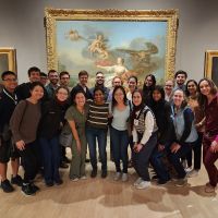 An Art of Neurology group photo in an art gallery in front of a large framed painting