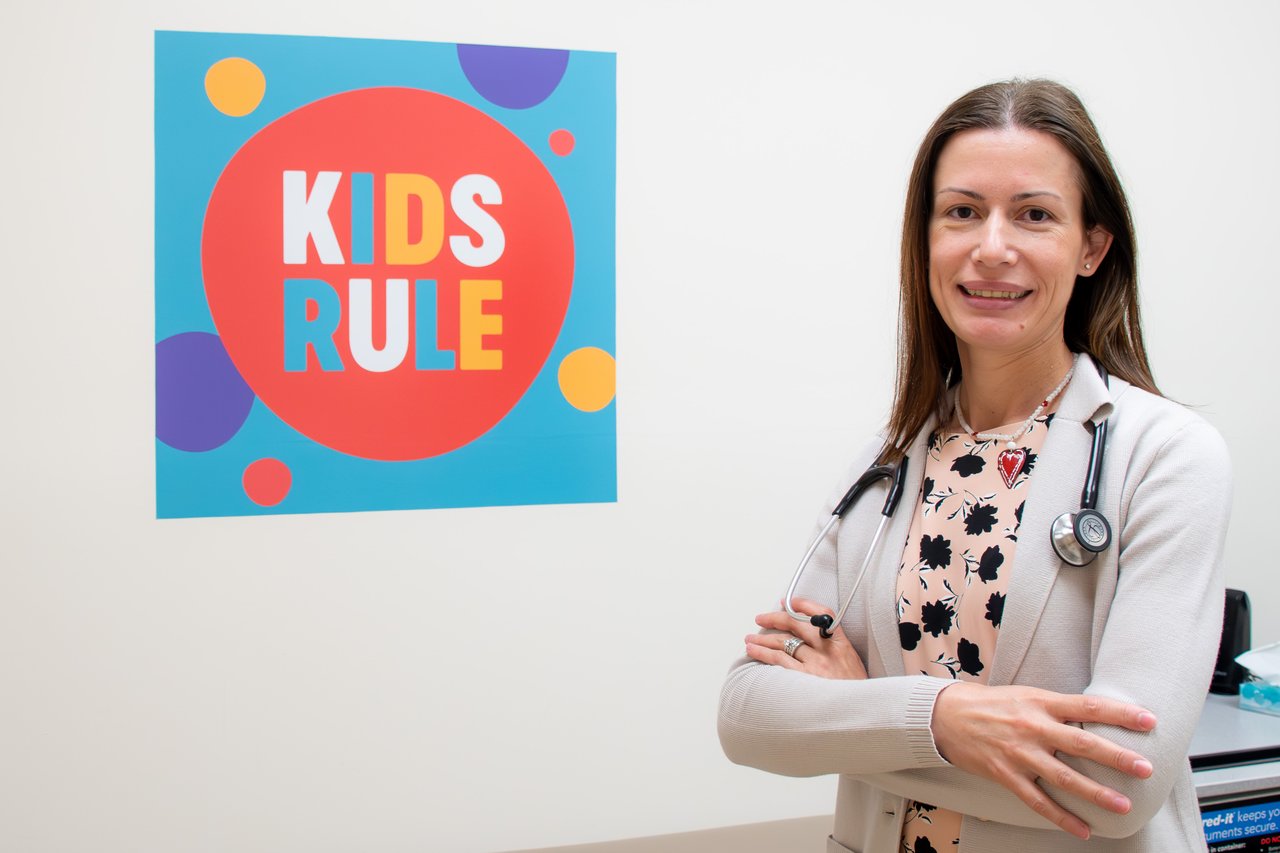 Dr. Cosper in her clinical space in front of the Kids Rule sign