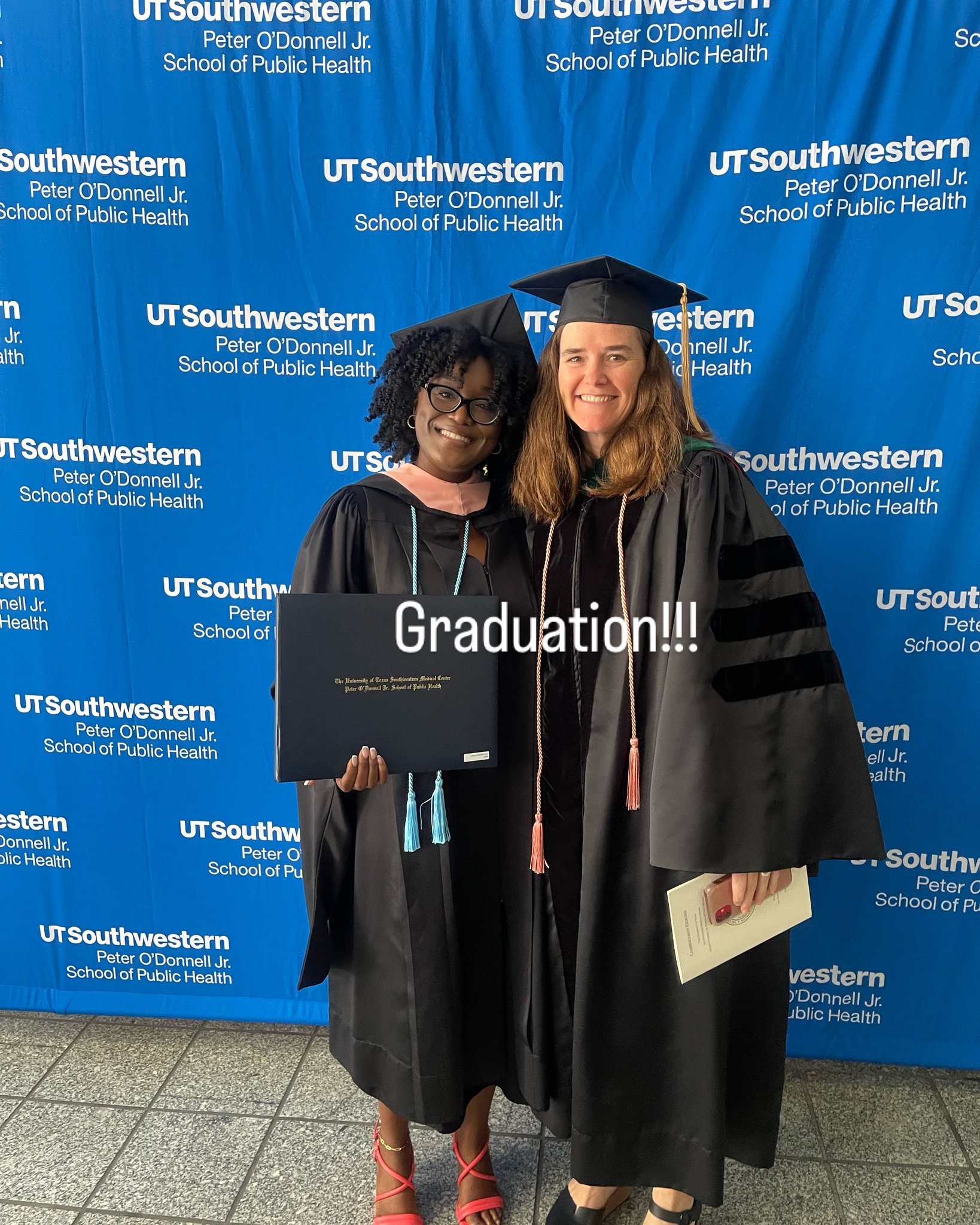 A photo of two smiling students in graduation robes