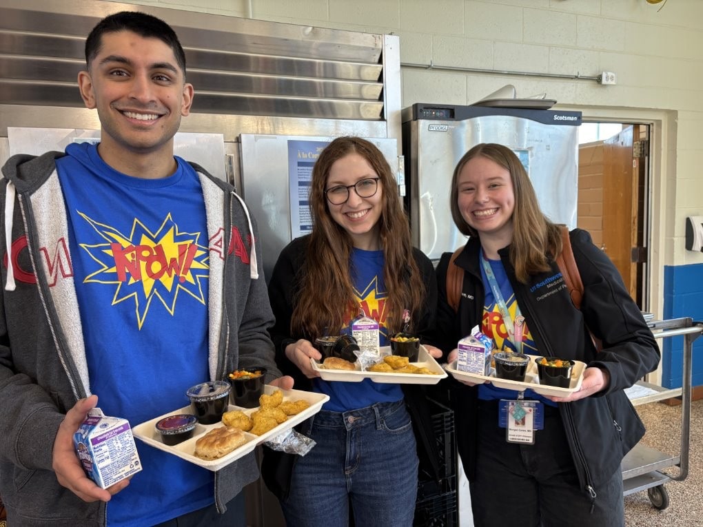 three students holding trays of food