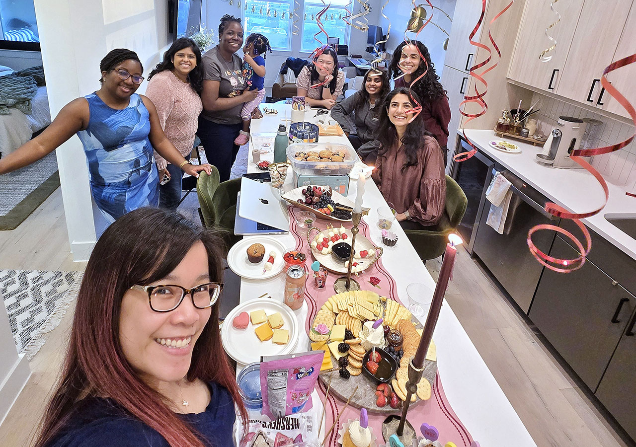 A selfie shot of the Fellows gathered in a decorated room with party food