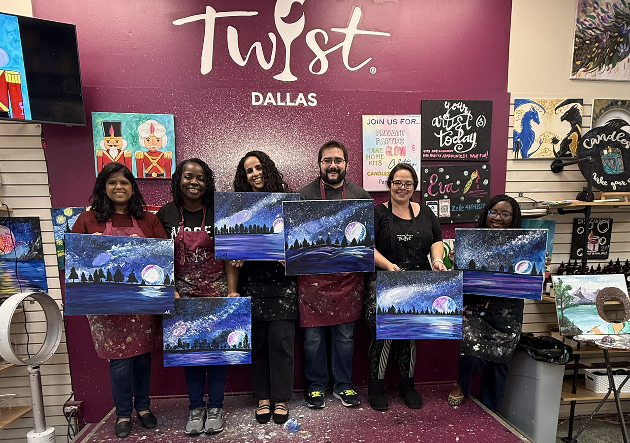 A group shot of the Fellows holding up paitings of the night sky with a rising room