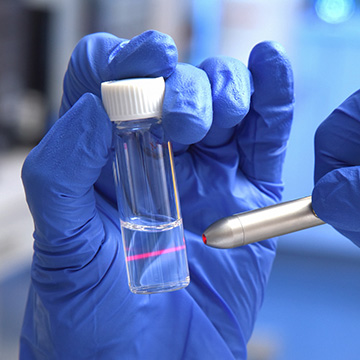 Hand wearing blue glove holding tube with specimen