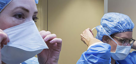 two surgeons donning masks