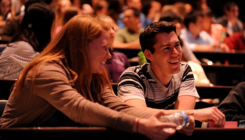 Two smiling students in a lecture hall