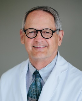 gray-haired doctor in white coat and tie wearing round glasses, Marc Swiontkowski, MD