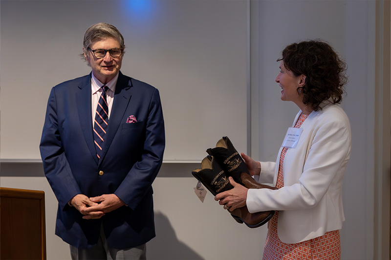 Woman holding cowboy boots while talking to man in blue jacket