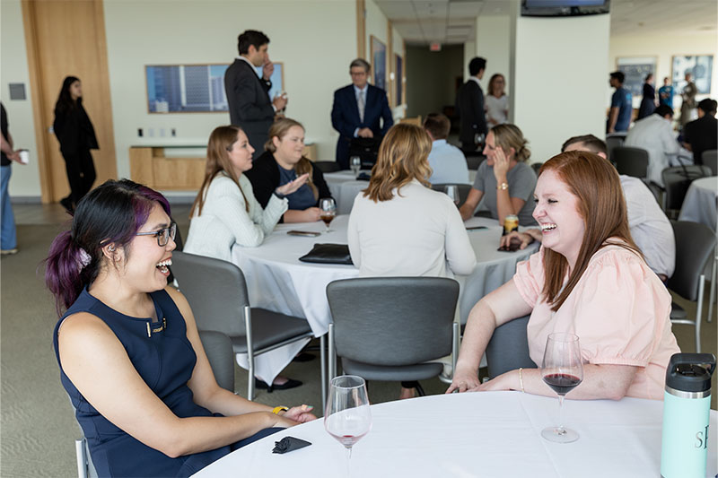 Thre women sitting at a table listenign intently to a speaker