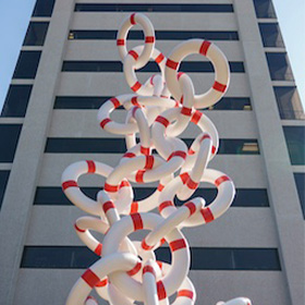 A red and white sculpture in front of a tall building