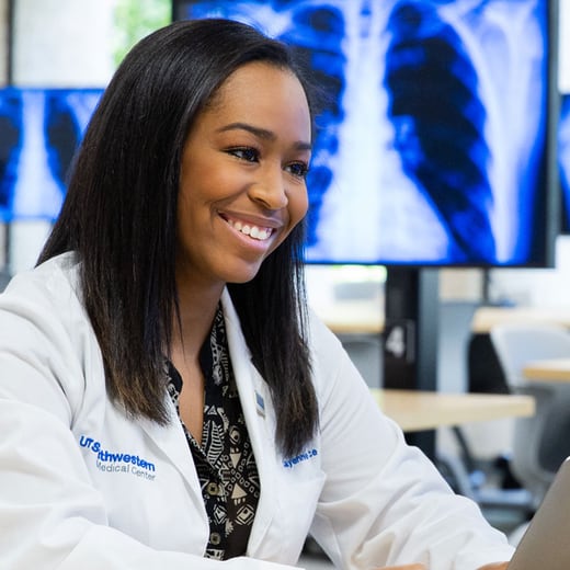 female student in white lab coat smiles