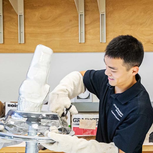 male student with white gloves working in lab