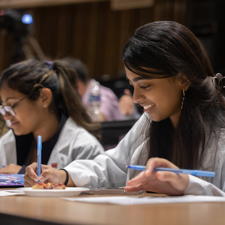 2 young women sitting and writing on papers