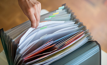 hand pulls papers out of top of accordion file