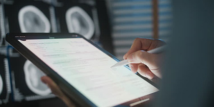 A person's hand writing on a tablet