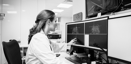 Dr. Davenport in a black and white photo looking at x-rays on a computer in the lab