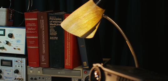 A lamp turned on with books in the background