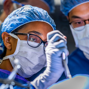 A close-up of Dr. Patel in the operating room with two other medical professionals