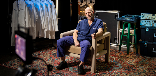 Dr. Thornton sitting in a chair, wearing blue scrubs