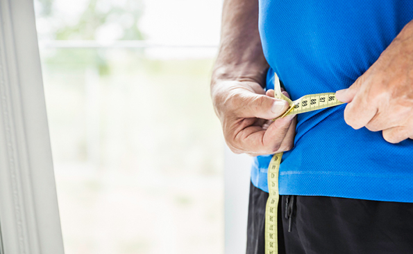 A man measuring his waist with a measuring tape