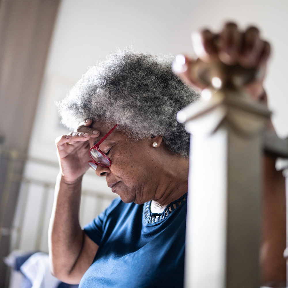 Senior woman with headache sitting in the bed at home