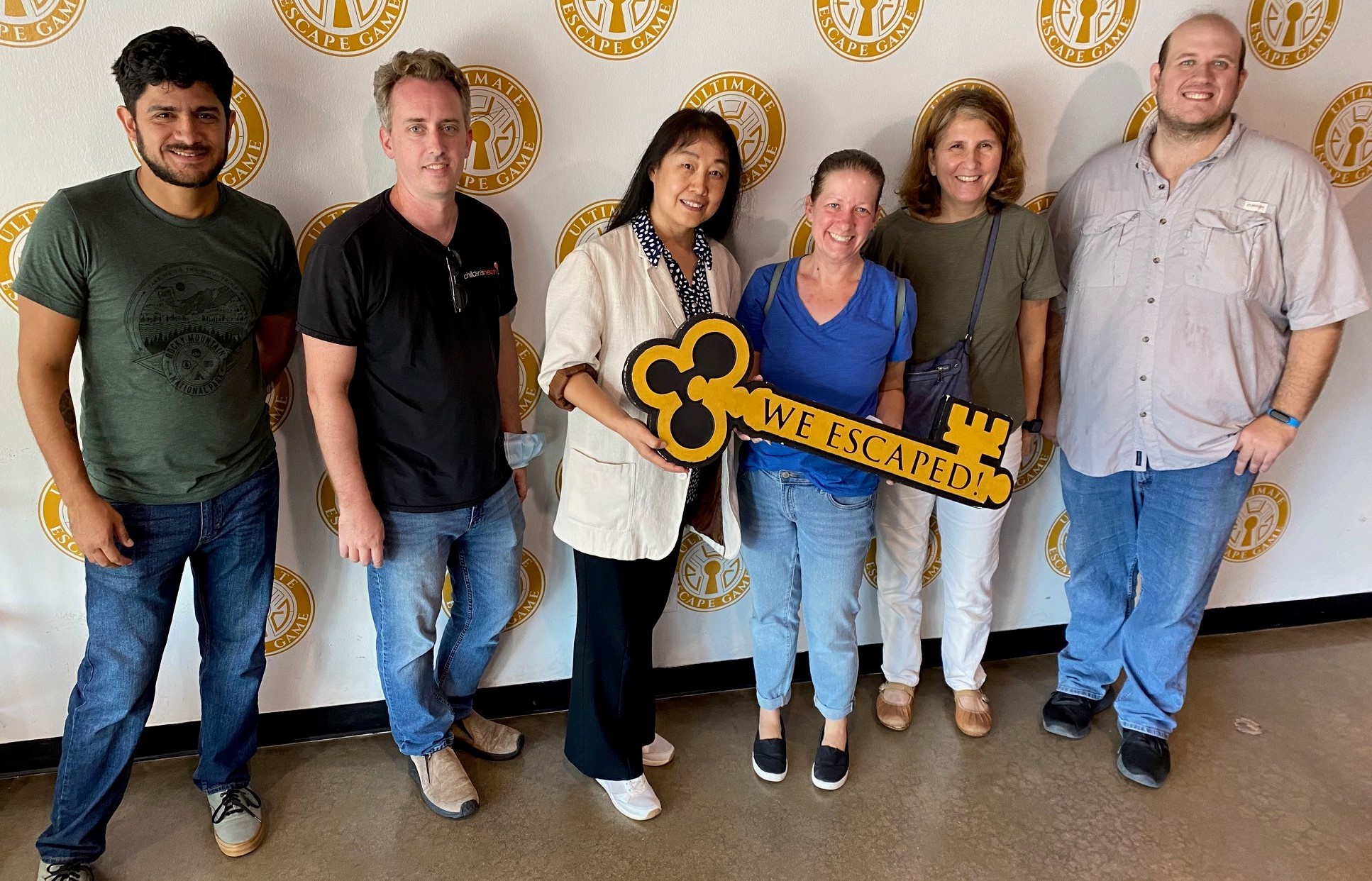 A group of people holding a large key that says: We escaped!