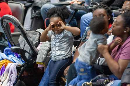 A little girl looks at the camera while making pretend goggles with her hands