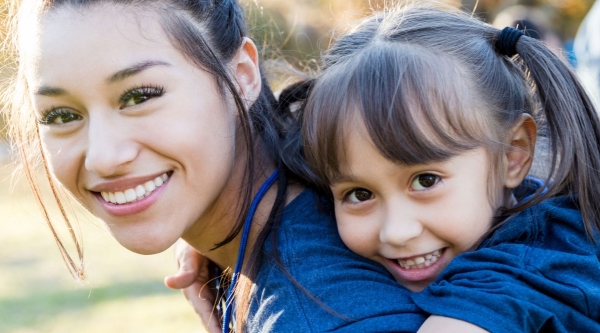 A woman carrying a smiling girl on her back