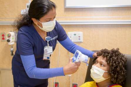 A nurse takes a patient's temperature using a laser thermometer