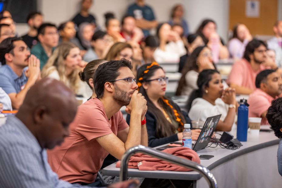 Audience members focus on fellow presenters' research findings during the symposium.